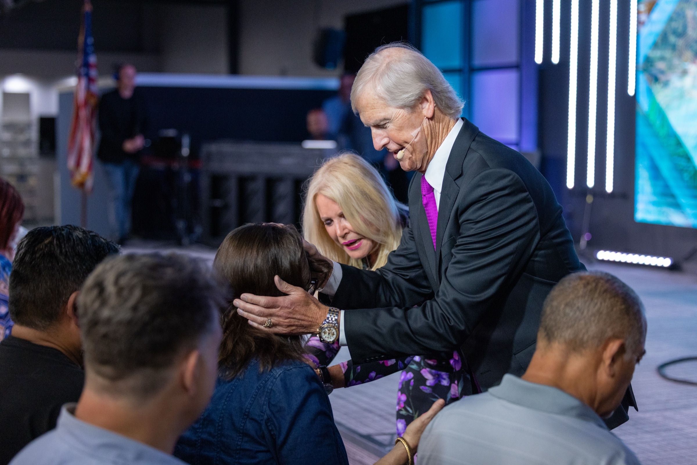 Apostle Theo and Dr Bev praying with a woman at the front of the church